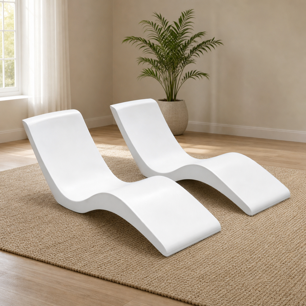 Two white resin contoured ledge loungers side-by-side on a woven rug in a bright indoor room, angled front view