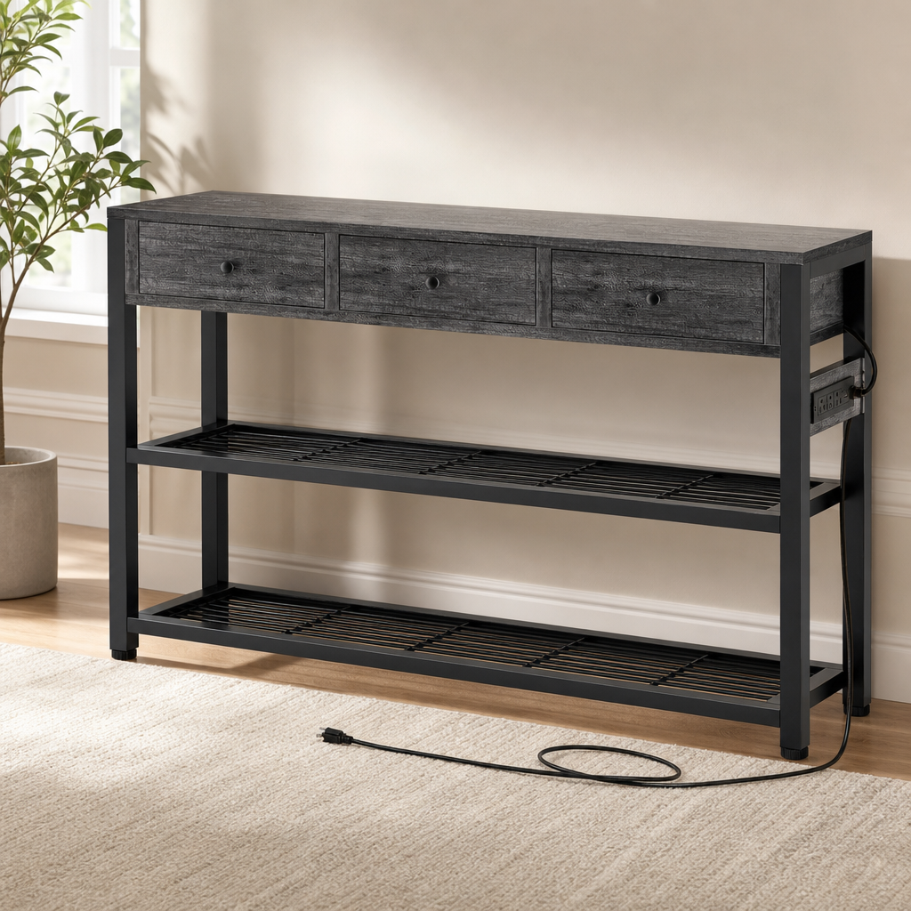 Grey wood-veneer console table with three drawers, black metal frame and two slatted shelves, angled front view with power c
