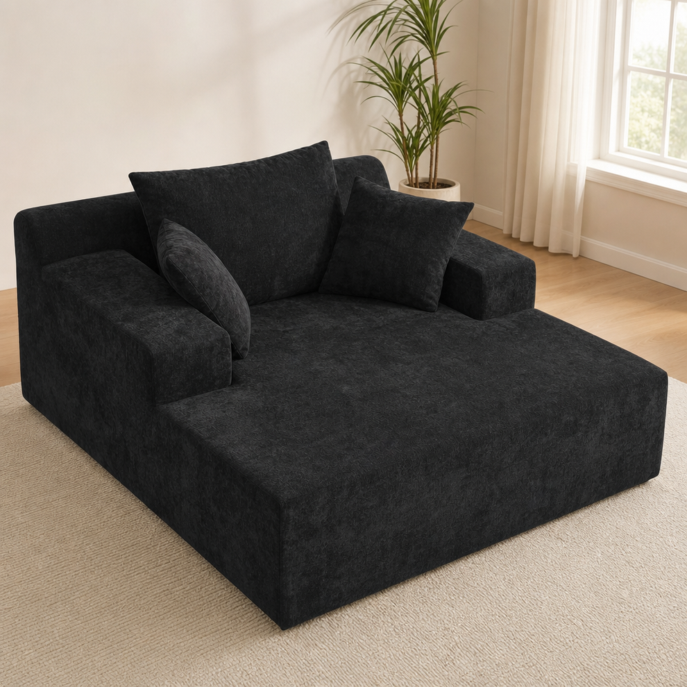 Dark grey boneless chaise lounge angled front view with deep seat and three soft cushions on a light rug