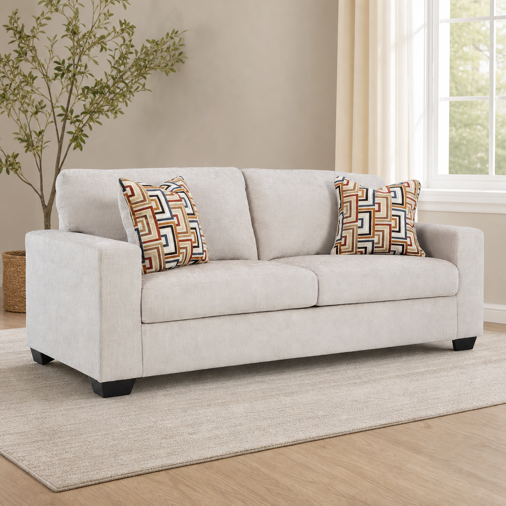 Stone beige chenille 85-inch sleeper sofa angled front view with two patterned accent pillows in a living room