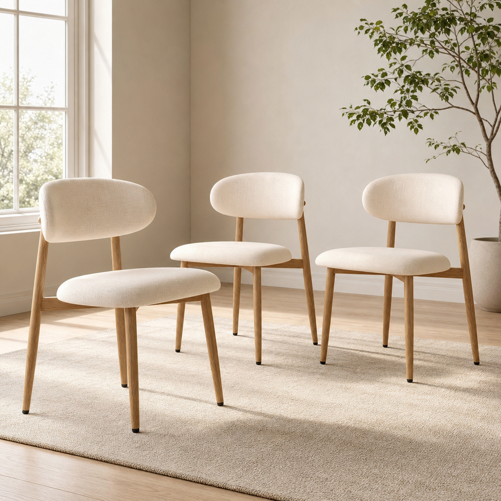 Beige upholstered dining chairs with wood‑grain metal legs on a light rug, angled front view