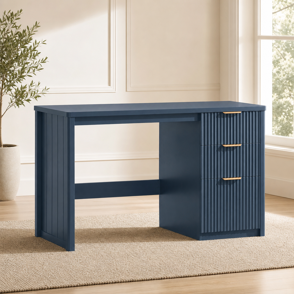 Navy blue fluted wood desk three-quarter front view on a rug with a potted plant nearby