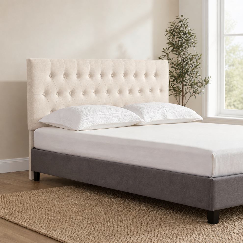 Beige tufted linen headboard shown angled front view with bed frame and pillows in a bright bedroom