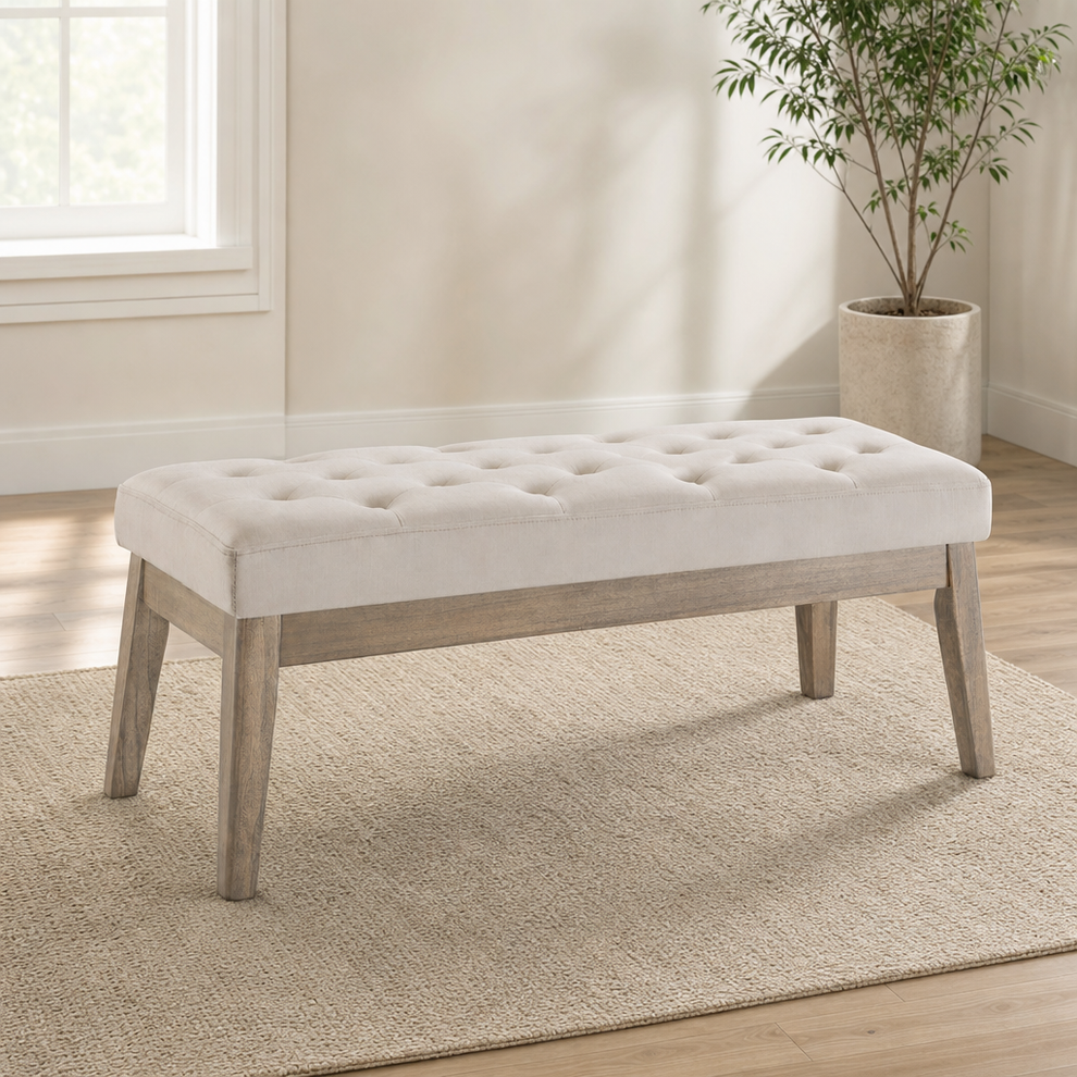 Light taupe velvet tufted bench with wooden base angled front view on a textured rug