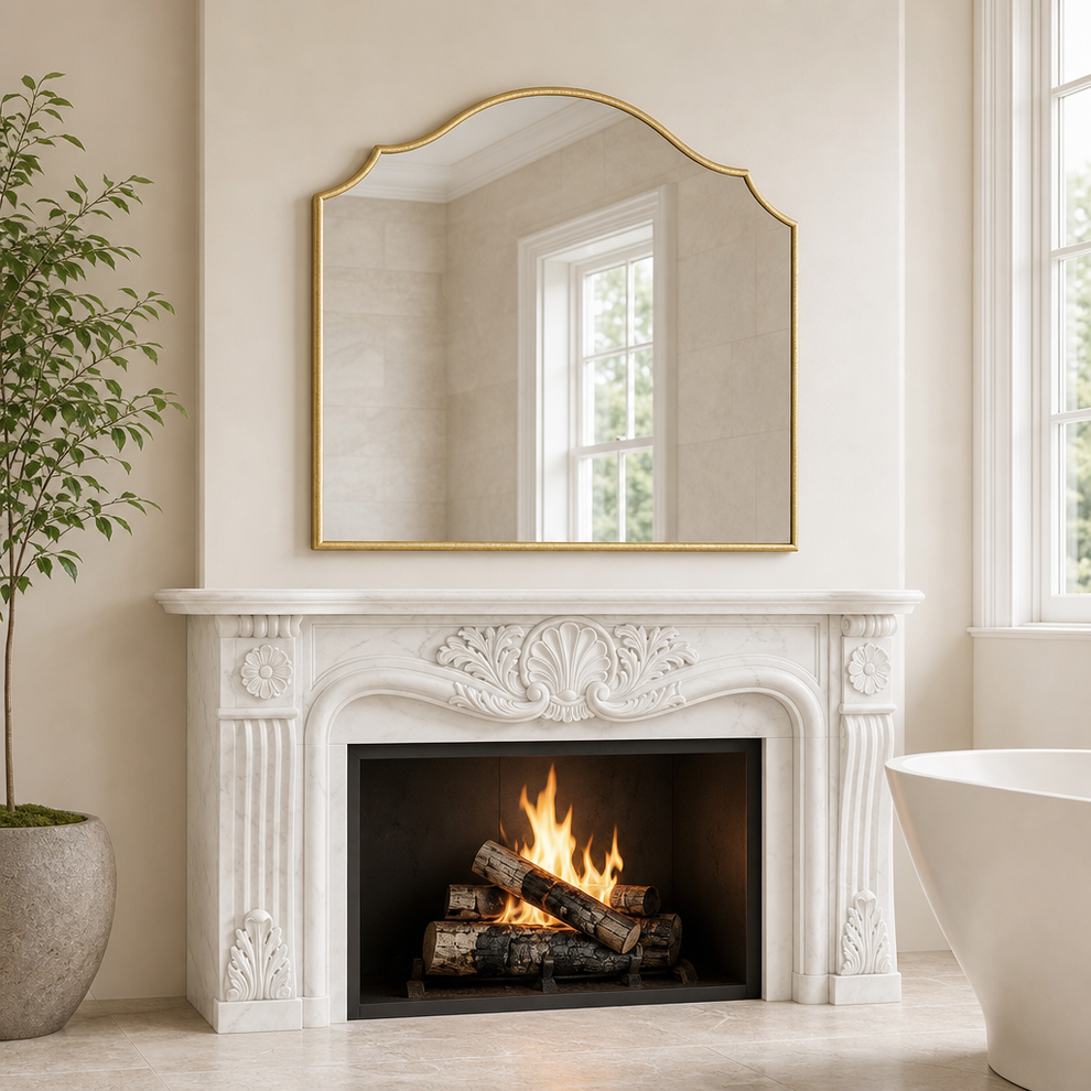 Gold scalloped-top arched wall mirror mounted above a white carved marble mantel with a lit fireplace