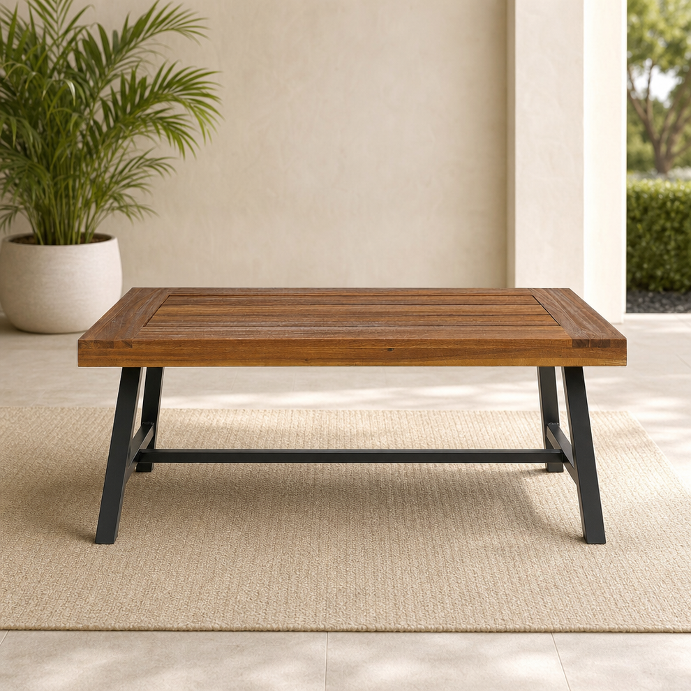 Christopher Knight Acacia Slat-Top Outdoor Coffee Table, Powder-Coated Metal Frame centered in a warm neutral furnished room
