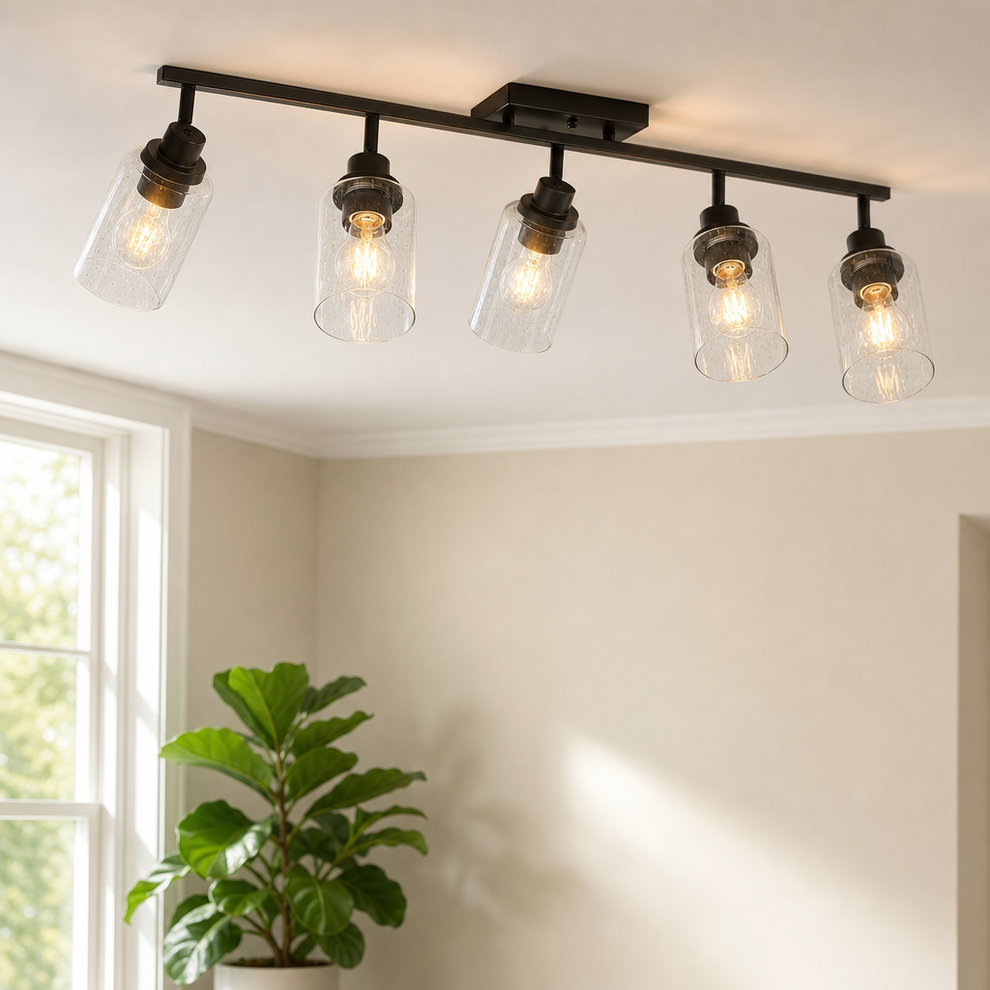 5-Light Track Lighting Fixture — Matte Black with Seeded Glass Shades centered in a warm neutral furnished room