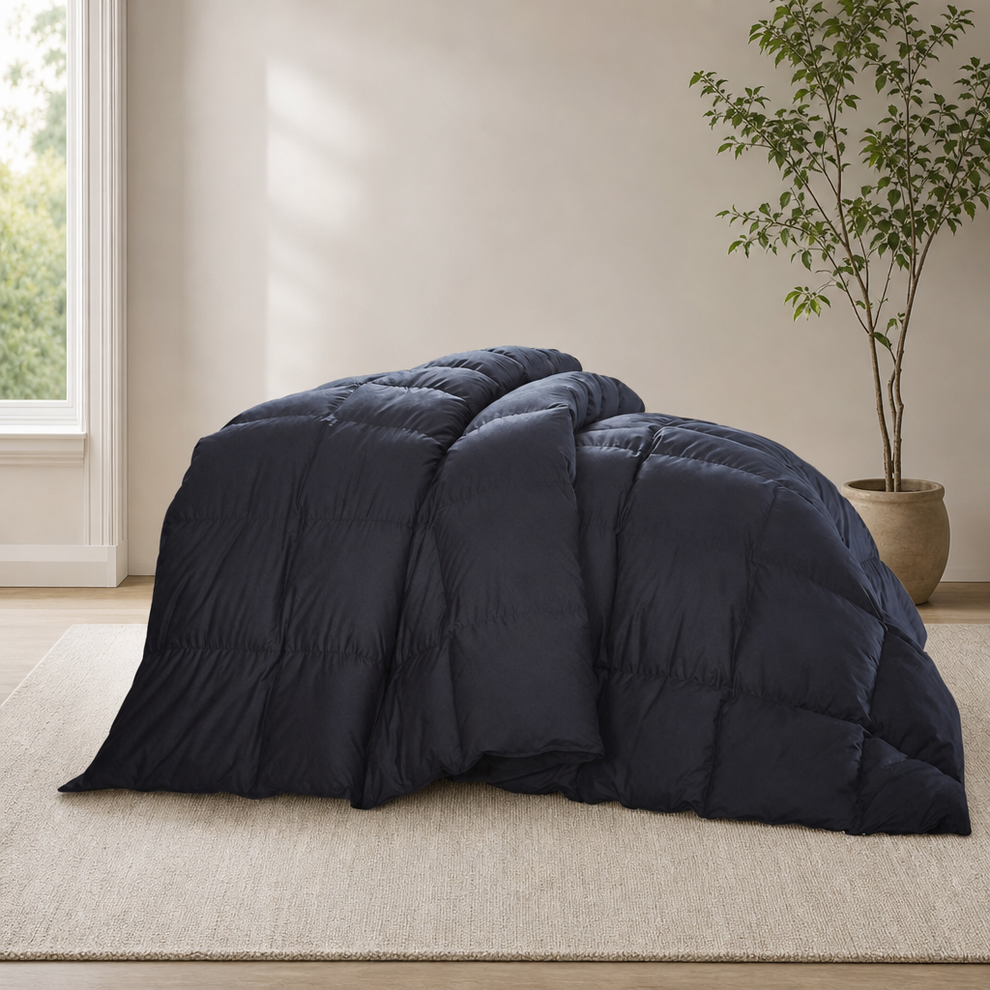 Black down comforter draped on a light rug, angled front view showing quilted baffle boxes and loft